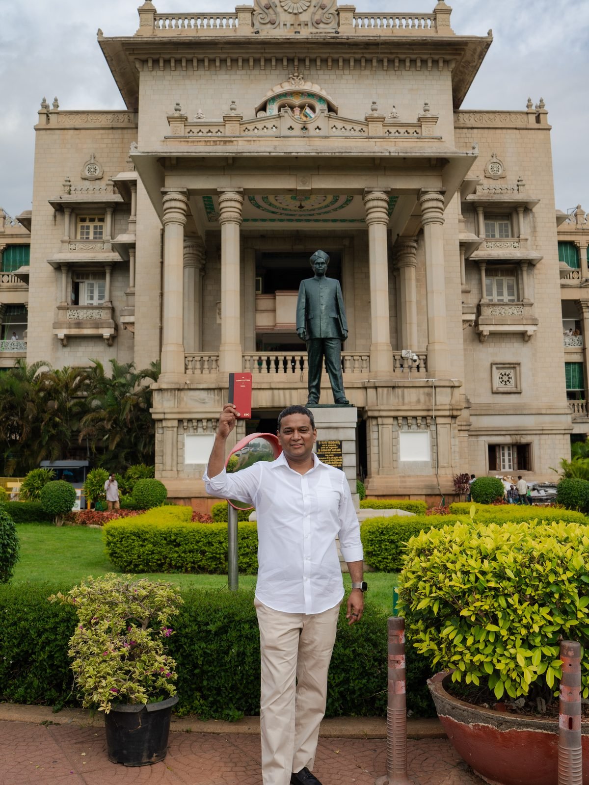 Mansoor Ali Khan holding up a copy of the Constitution of India.